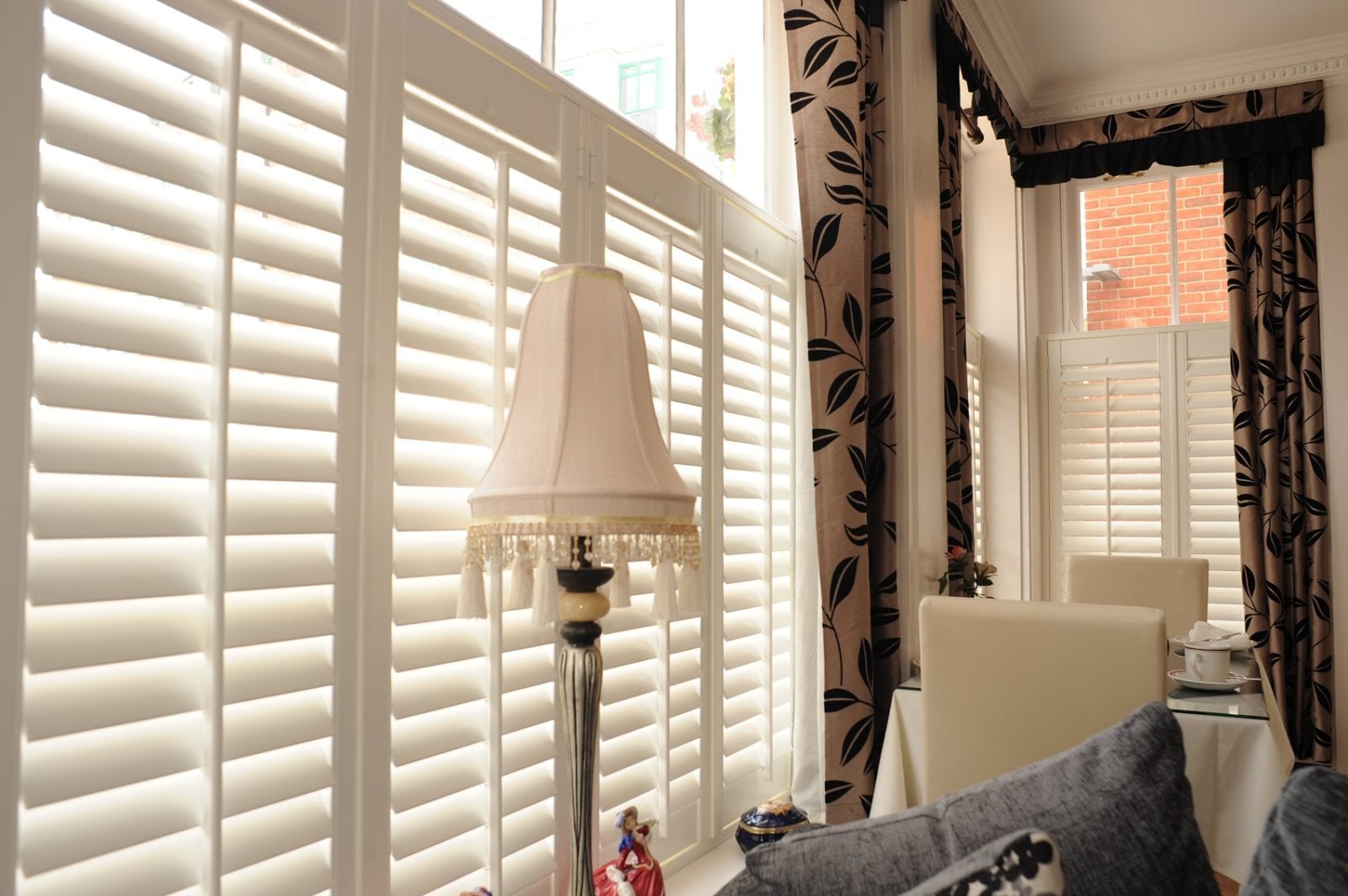 Full height white shutters with sunlight coming through the louvres in a dining room