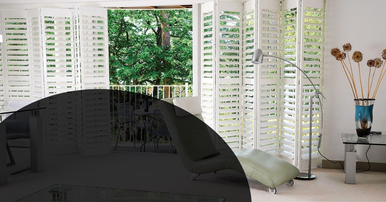 Tracked shutters beside a balcony with a chaise longue in a bright room