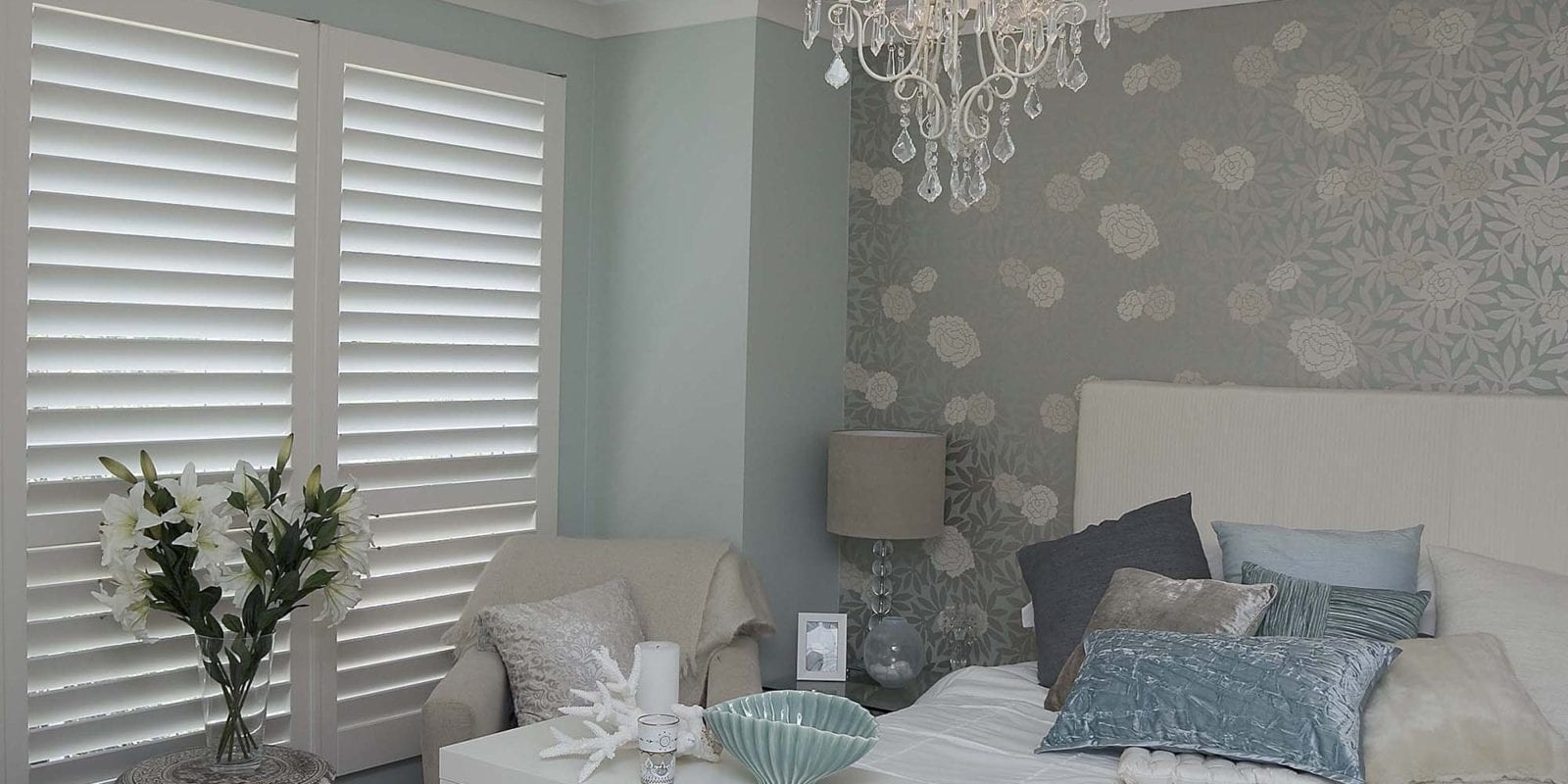 Bedroom with full height shutters and a wide bed