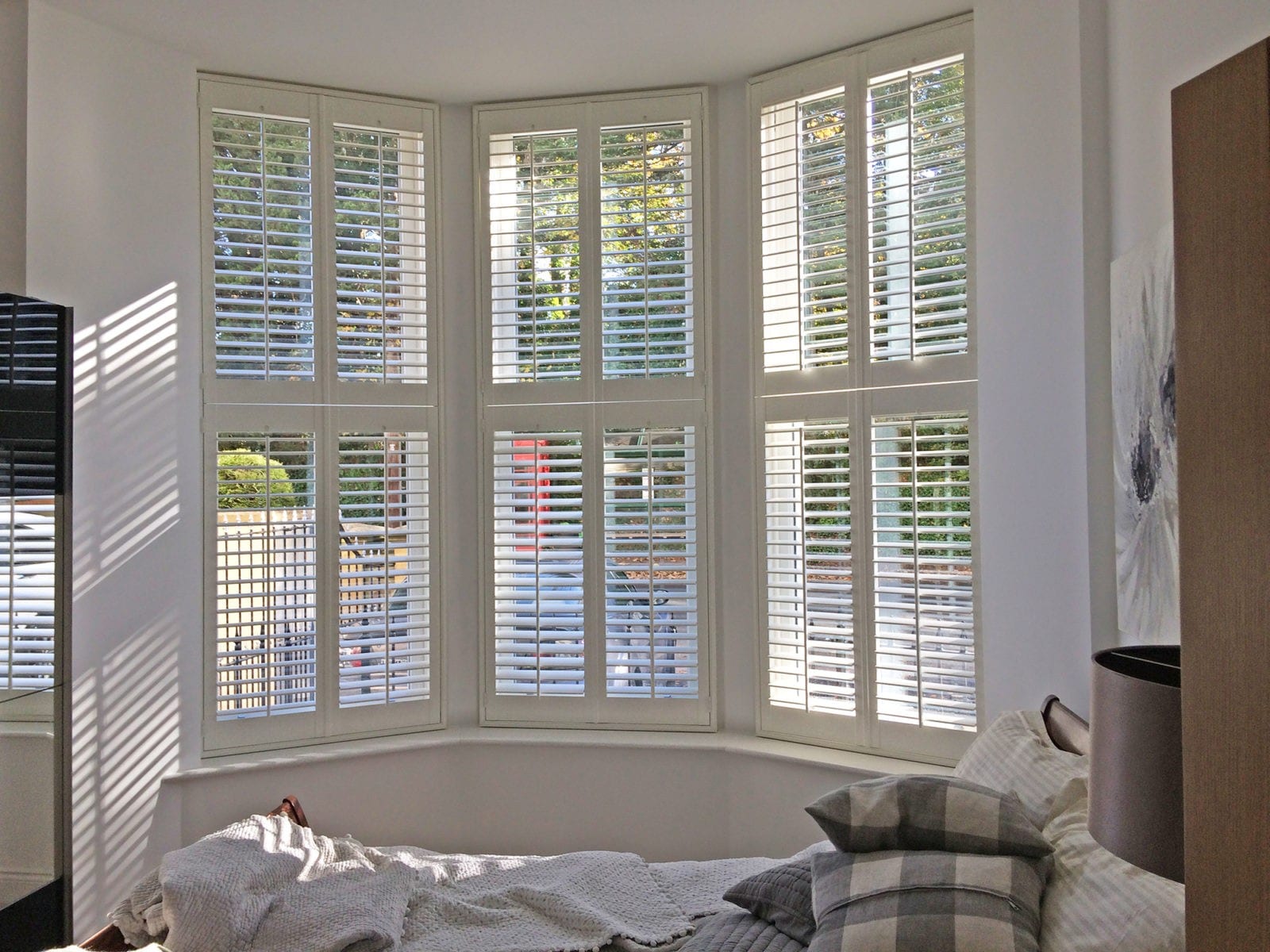 Tier on tier shutters fitted to a bay window in a bright room