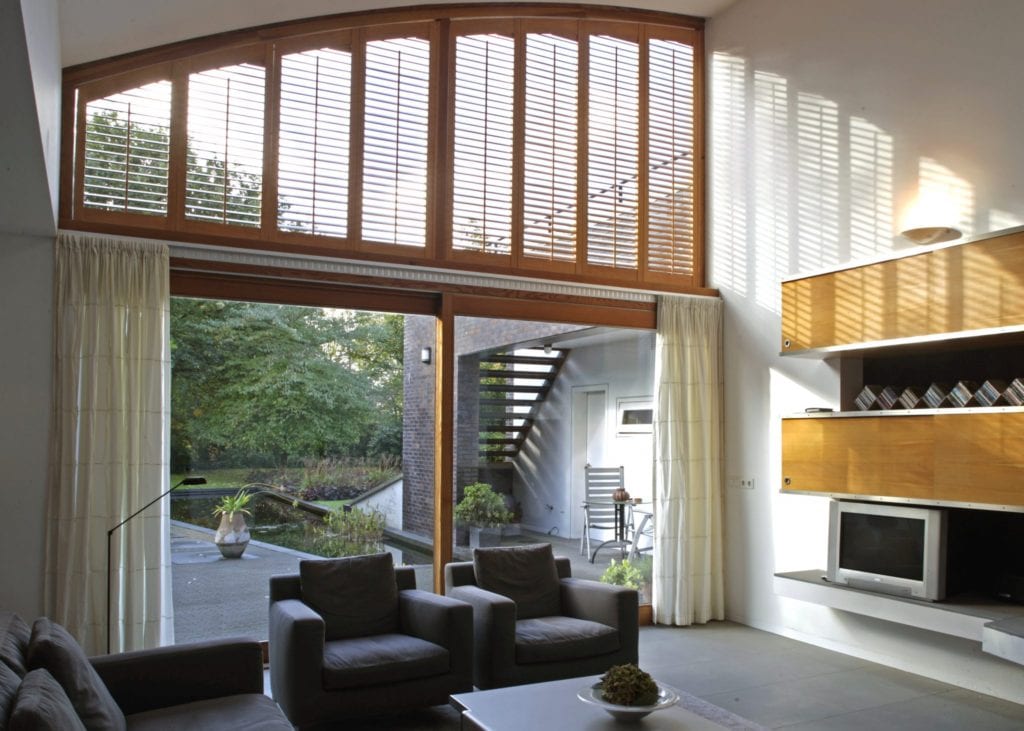 Arched special shaped shutters above a large glazed door in a modern living space