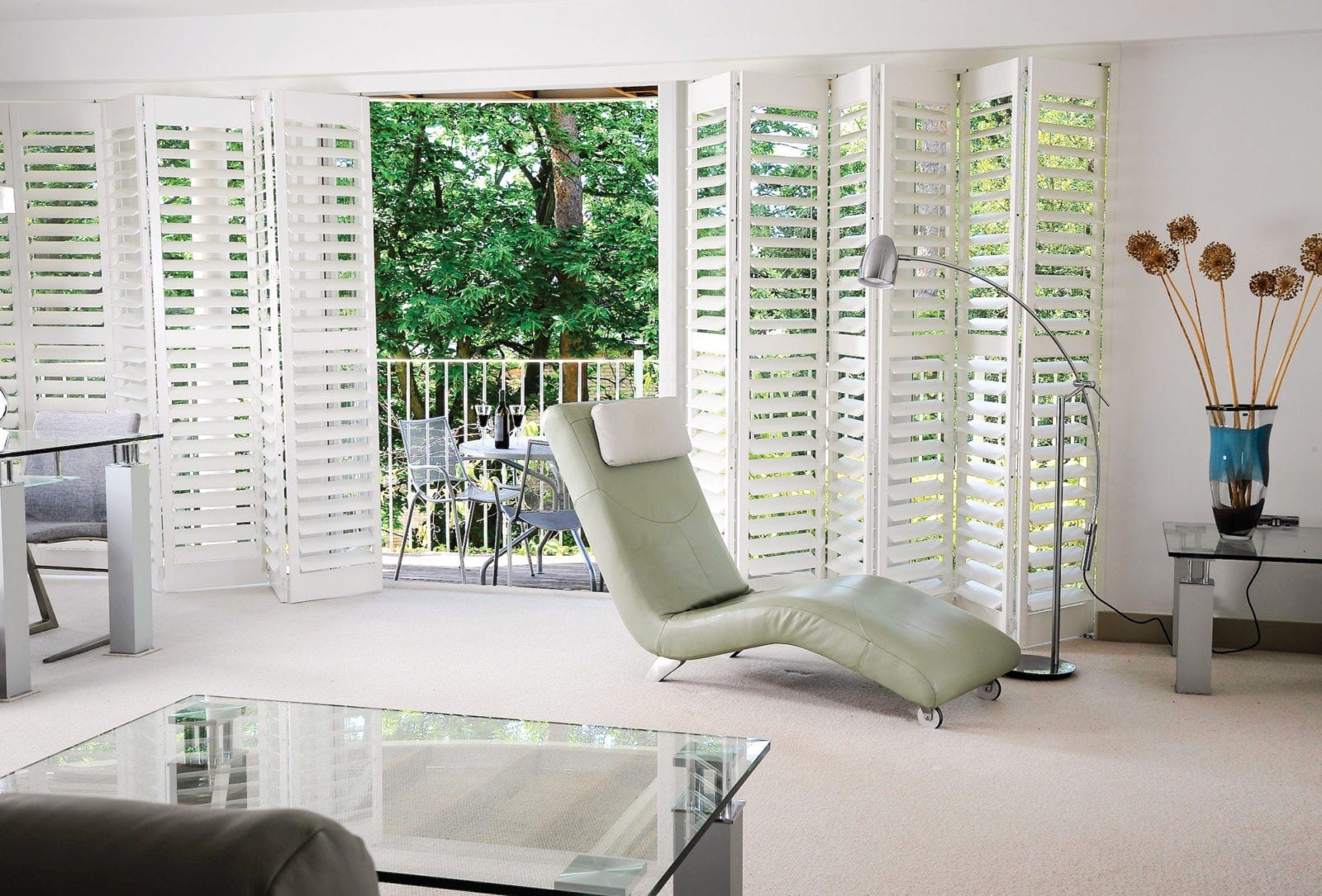 Bi-fold tracked shutters opening onto a balcony in a bright living room